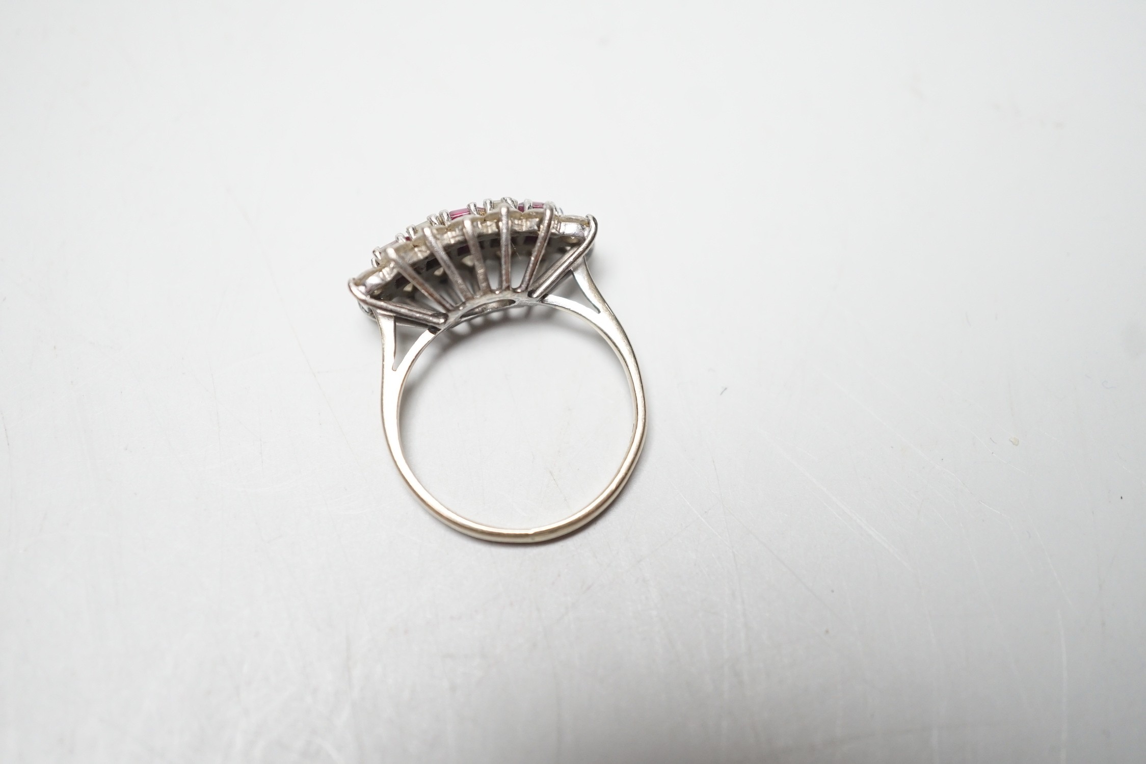 A modern 18ct white gold, square cut ruby and round and baguette cut diamond set cluster ring, size L, gross weight 3.9 grams.